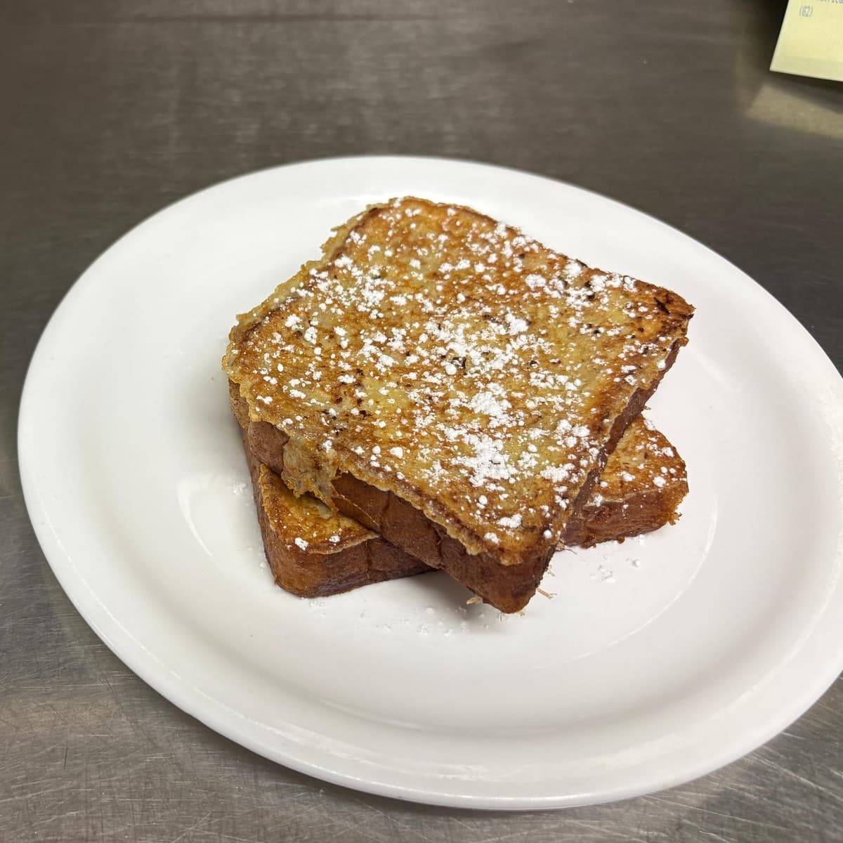 French Toast — Powdered sugar tops this French toast, with maple syrup served alongside
